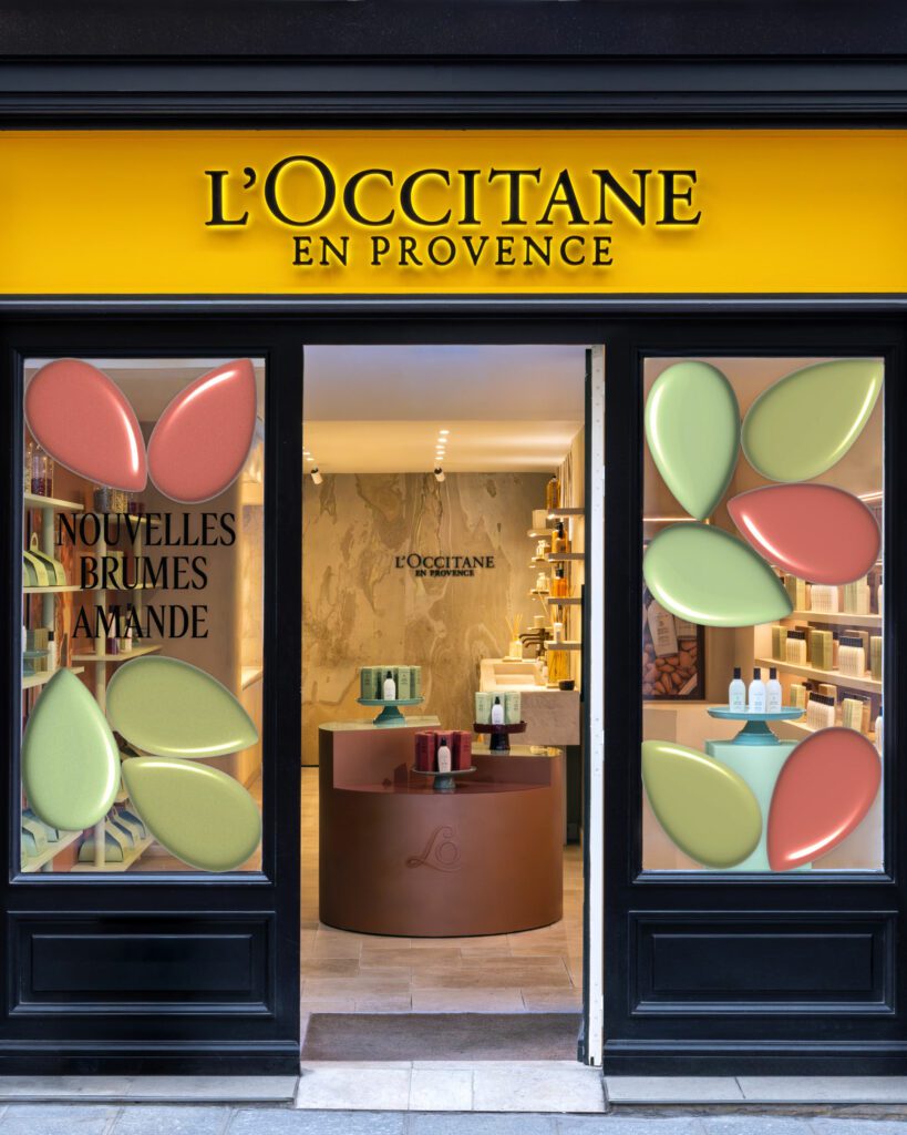 Entrée de la boutique L'Occitane du Marais, enseigne jaune et vitrines de l'animation Amande, vue de face · vrai studio