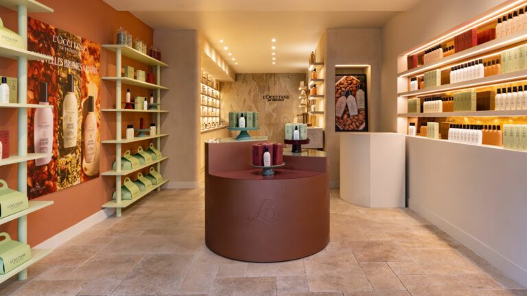 Vue d'ensemble de la boutique L'Occitane du Marais, comptoir circulaire, murs terracotta et étagères lumineuses · vrai studio